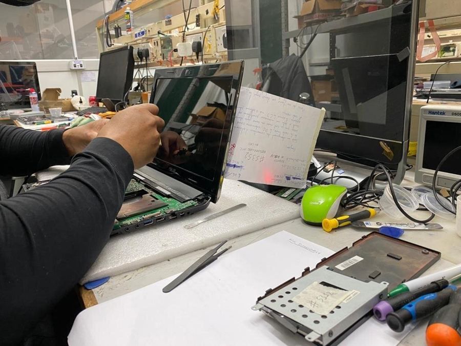 A technician replacing a laptop screen at the workshop bench